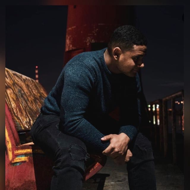 Man in blue sweater sat on bench at night